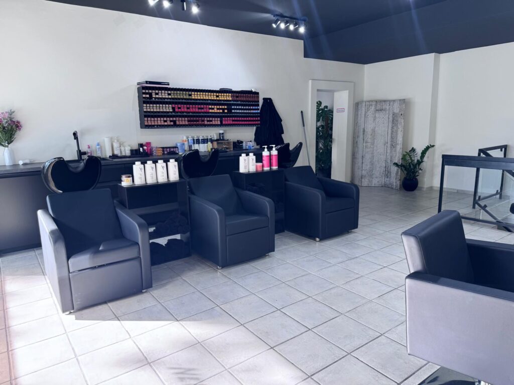 Waschbereich mit schwarzen Waschsesseln und Pflegeprodukten bei Mey’s Hairlounge in München