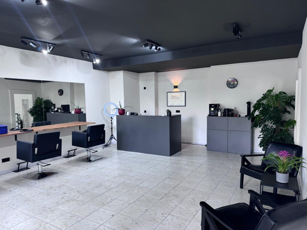 Salonansicht mit Spiegelwand, Bedienplätzen und Empfangstheke von Mey’s Hairlounge